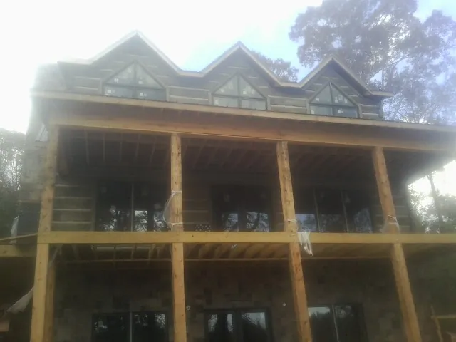 Dormers and porch framing on a large log home under construction — Roof Coating work by our crew in Mohler