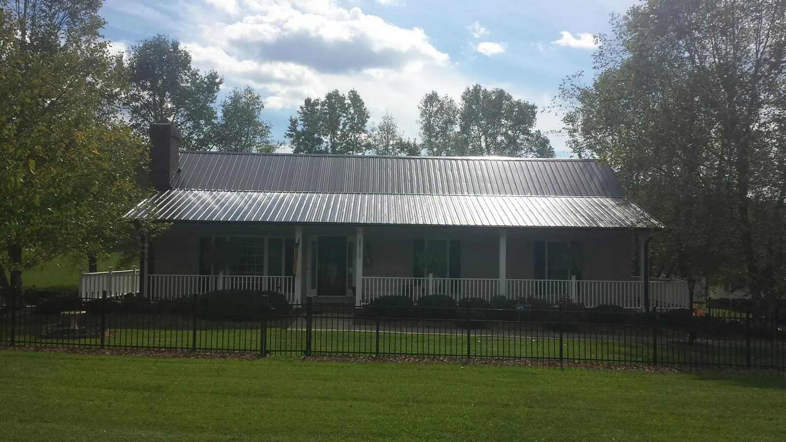 Gray metal roof on a brick ranch with a full width front porch — Gutter Guard Installation work by our crew in Mohler