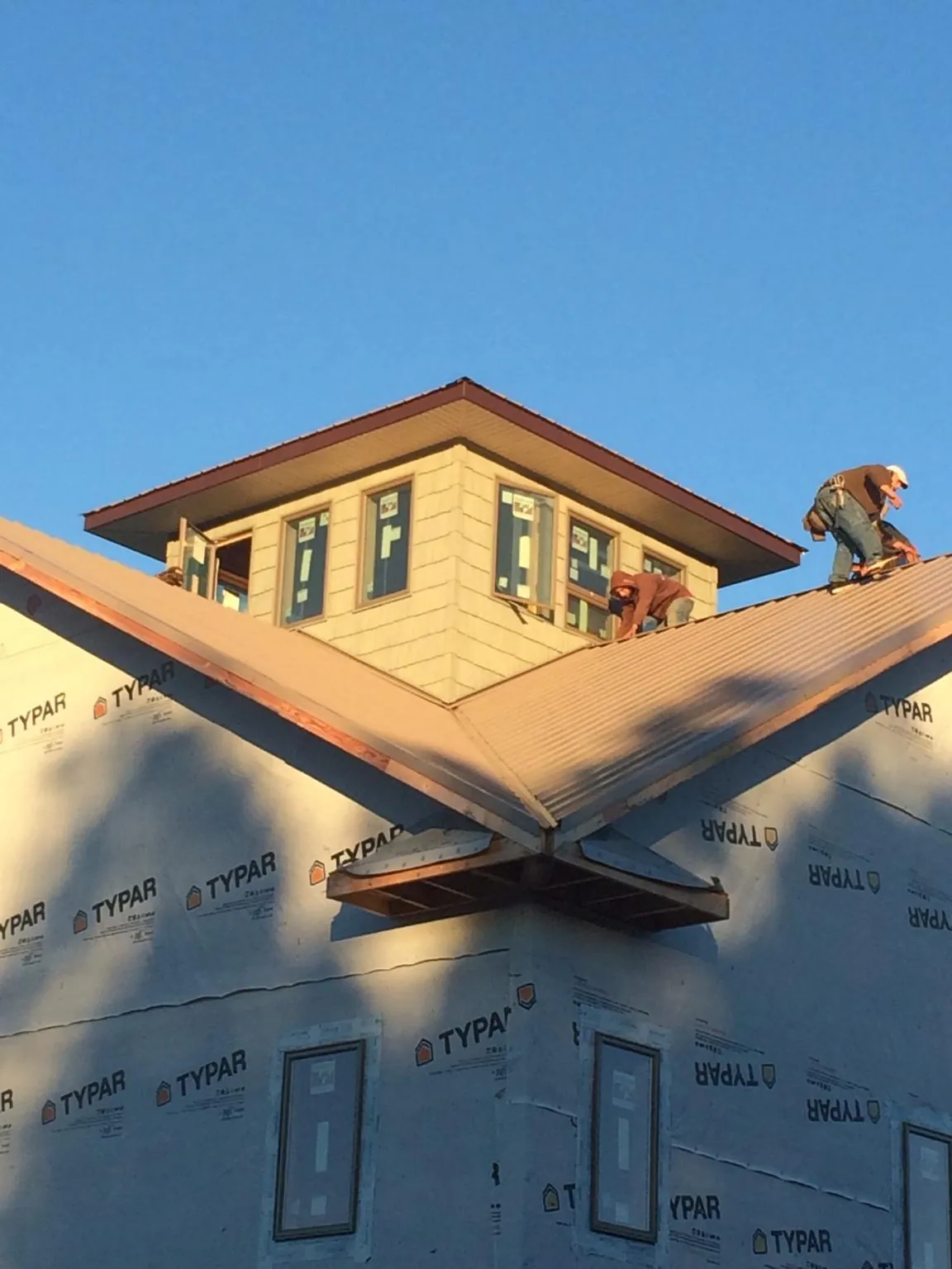 Roofers working around a rooftop cupola on a new metal roof at sunset — Roof Waterproofing in Mohler by Roofing Brothers